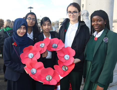 School children in uniform holding a poppy wreath at a public Remembrance ceremony 